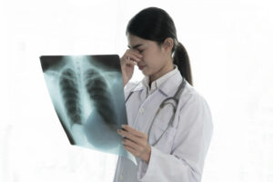 Asian woman doctor reading a chest x-ray showing pneumonia