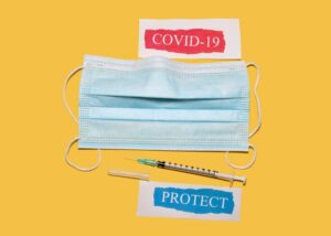 A mask, needle, and syringe as symbols to protect from COVID-19
